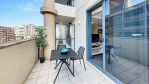 Ein Balkon mit Tisch und Stühlen, einem Blumentopf und Blick auf die Stadt.