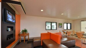 A lobby with a seating area, a TV mounted on the wall, and a small table with a plant. - Cozy Queen Bed Room|Pool|Free WiFi (MERIDIAN)