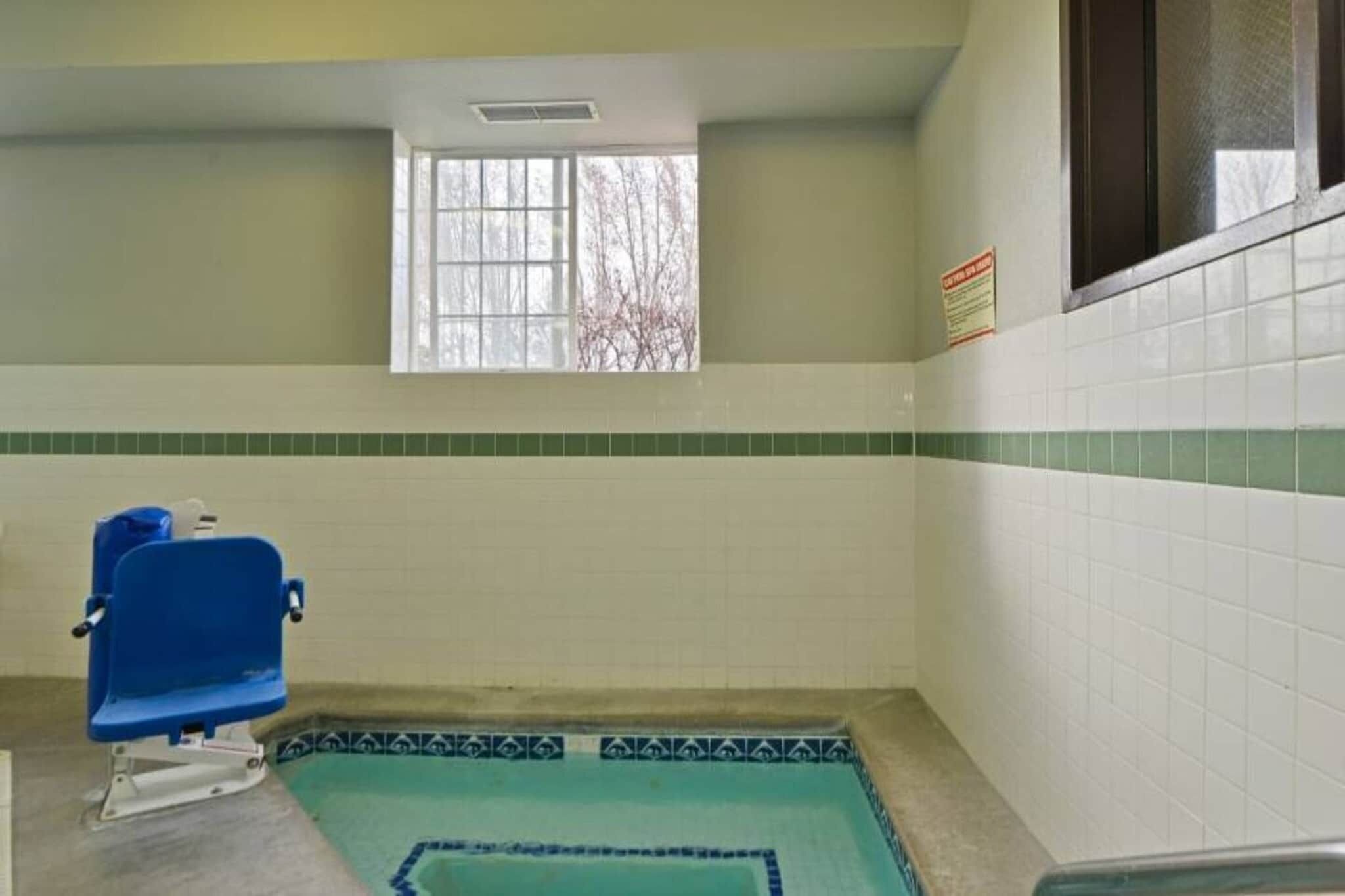A small room with a window, a blue chair, and a tiled floor.