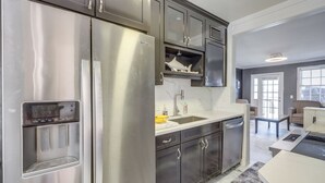A modern kitchen with stainless steel appliances, dark cabinetry, and a built-in water dispenser. - Poolside Fun! Waterfront Gem Near San Marco Square (Jacksonville)