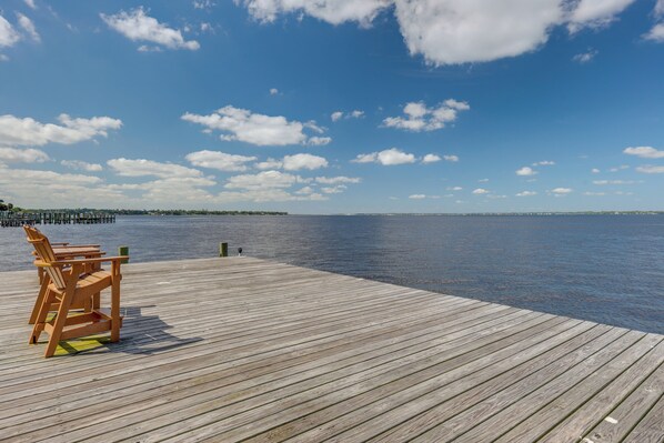 Un muelle de madera que se adentra en aguas tranquilas bajo un cielo despejado.