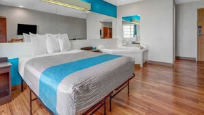 Ein modernes Hotelzimmer mit einem großen Bett, einem Badezimmer mit Spiegel und Holzboden.