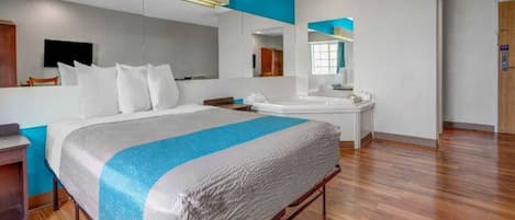 Een moderne hotelkamer met een groot bed, een badkamer met een spiegel en een houten vloer.