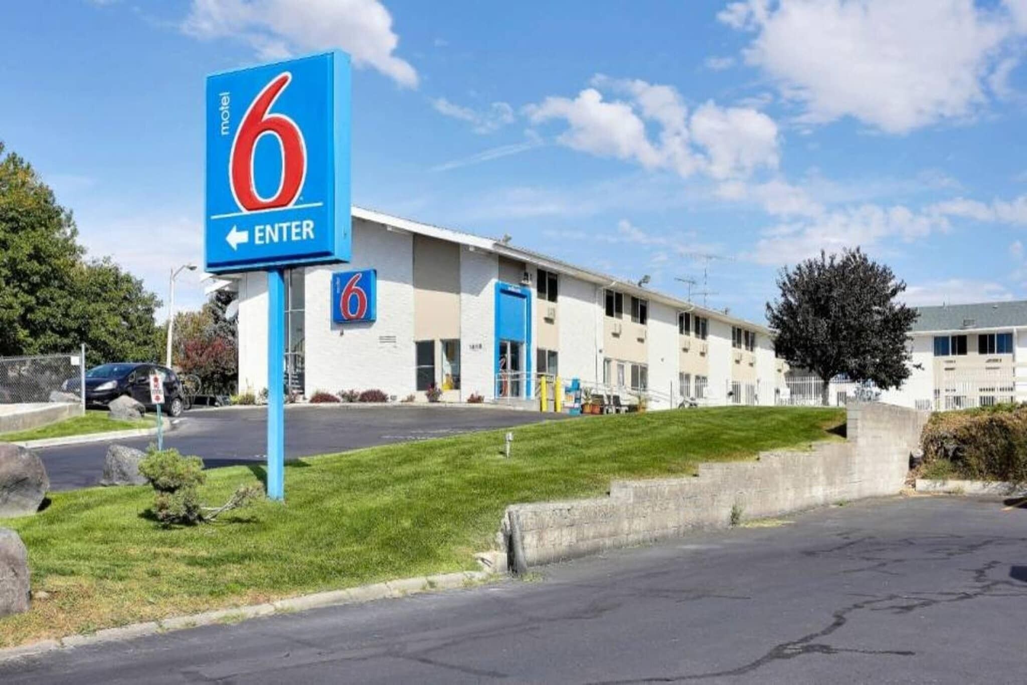 A motel with a prominent '6' sign, a parking lot, and a building with multiple doors.