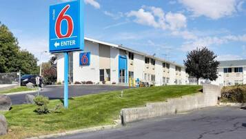 A motel with a prominent '6' sign, a parking lot, and a building with multiple doors.