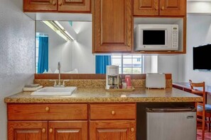 A kitchen with wooden cabinets, a microwave, a coffee maker, and a toaster.