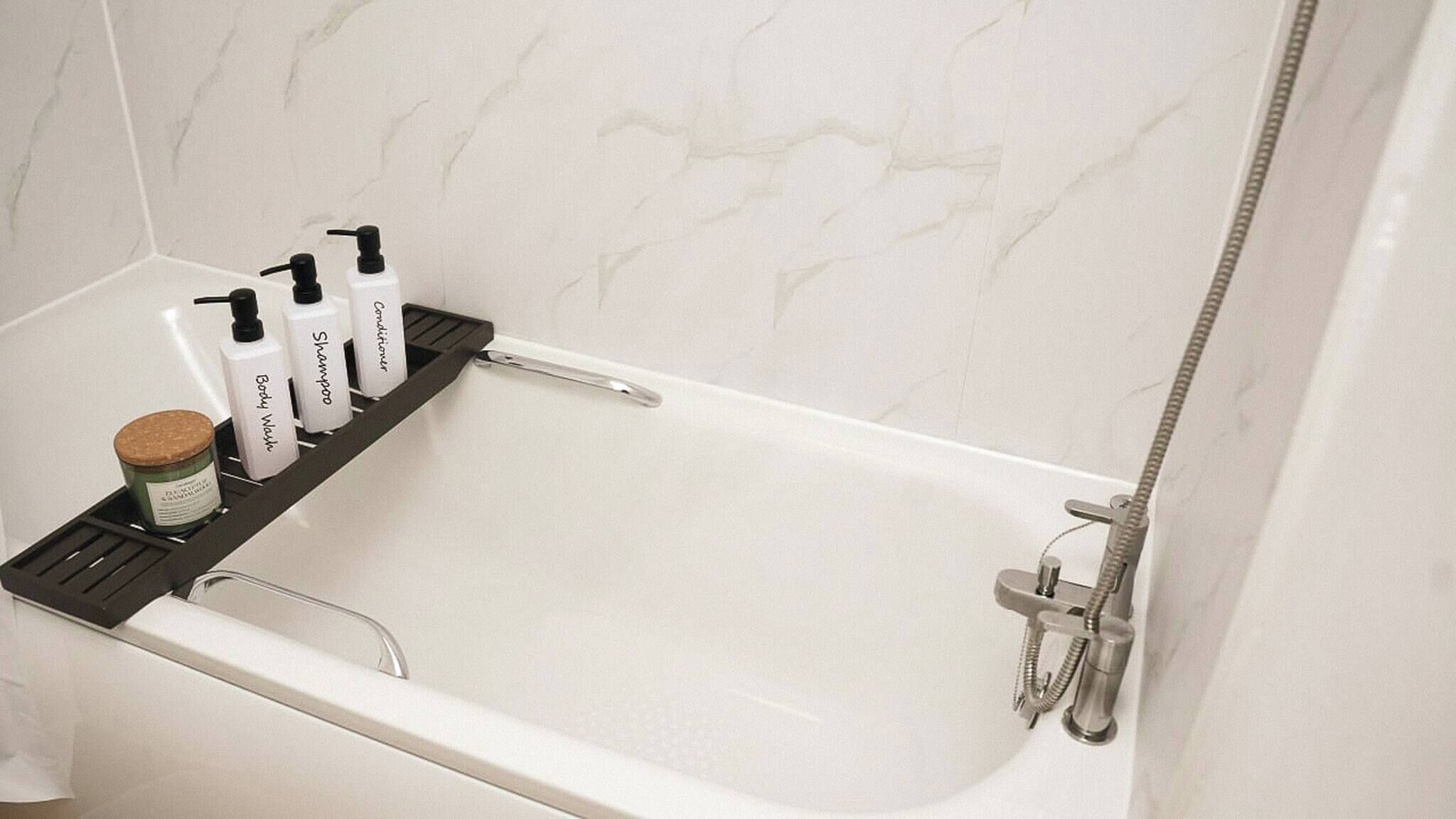 Une salle de bain avec une baignoire, une étagère contenant des articles de toilette et une pomme de douche.