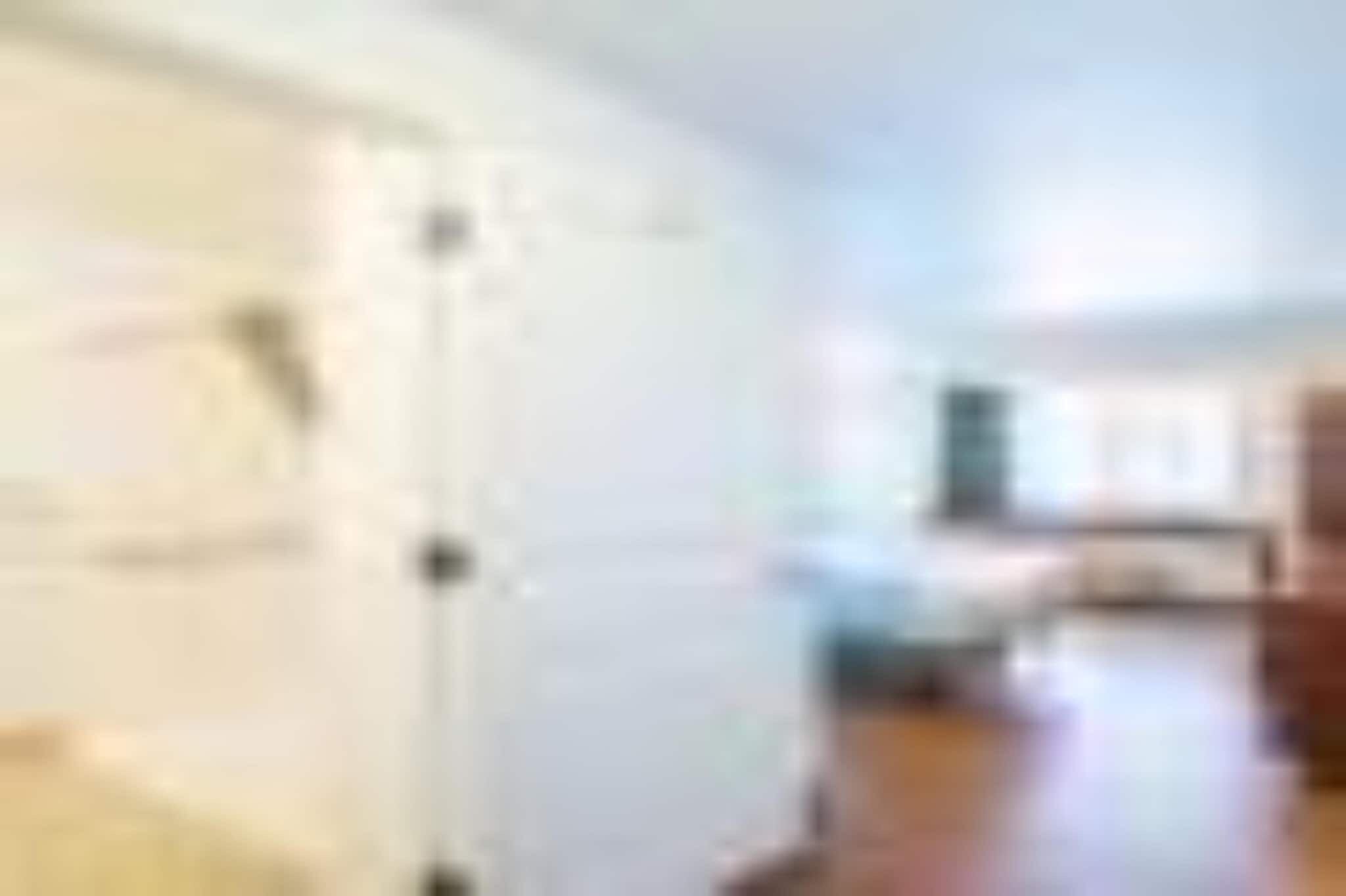 A room with a white door, a bed, and a window.