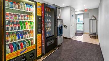 Een automaatgedeelte met diverse dranken en snacks, een trap en een deur naar een andere ruimte.