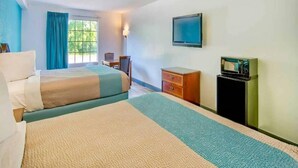 A hotel room with two beds, a desk, a chair, a television, and a small cabinet.