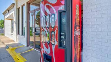 Una máquina expendedora de Coca-Cola frente a un edificio con puertas de vidrio.