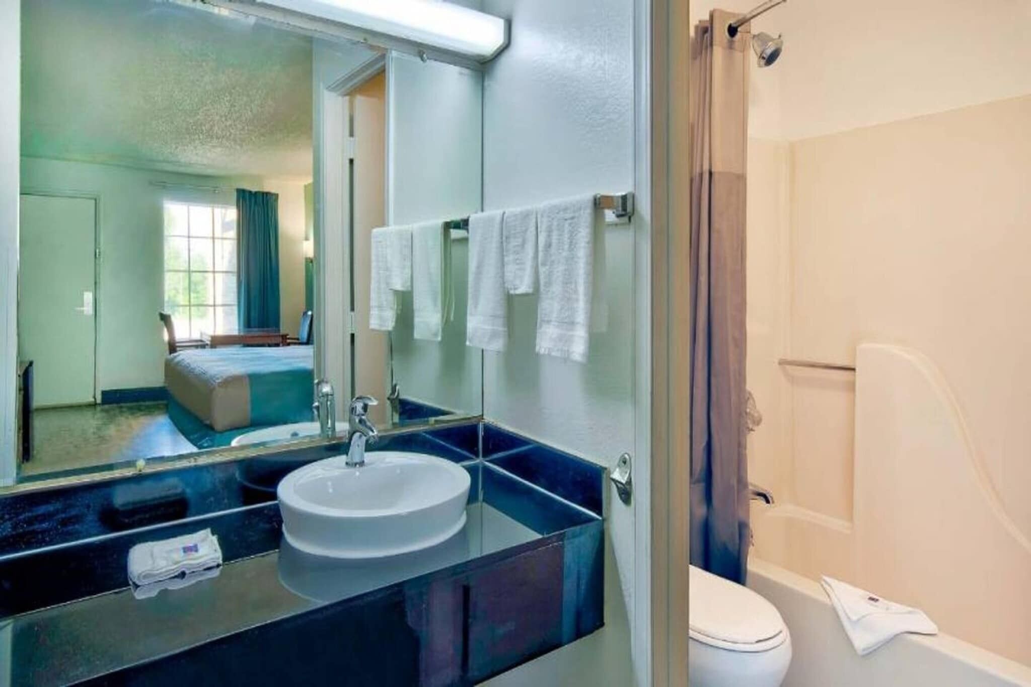 A bathroom with a sink, mirror, and towel rack.