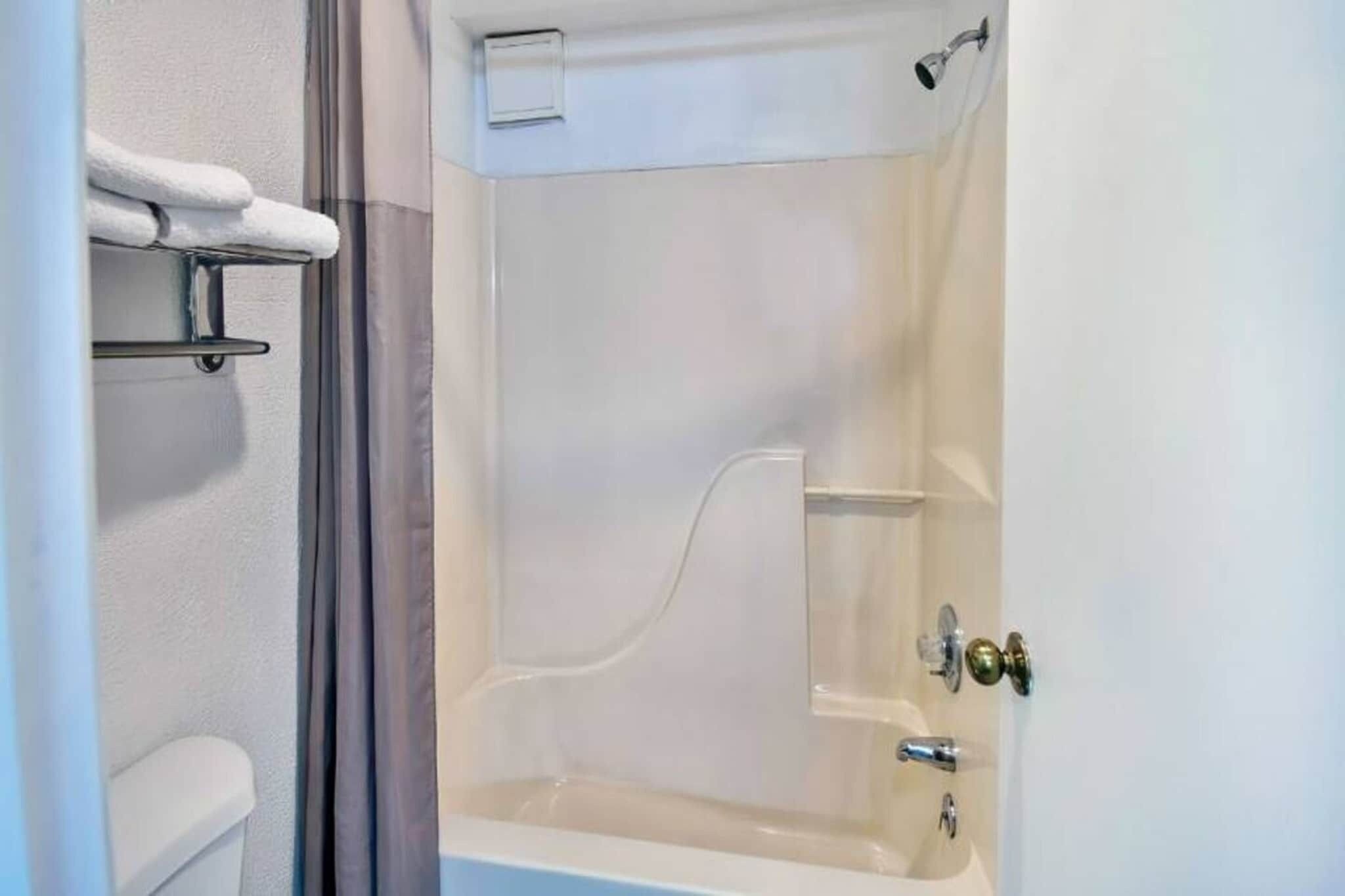 Een badkamer met een bad, een toilet en een handdoekhouder.
