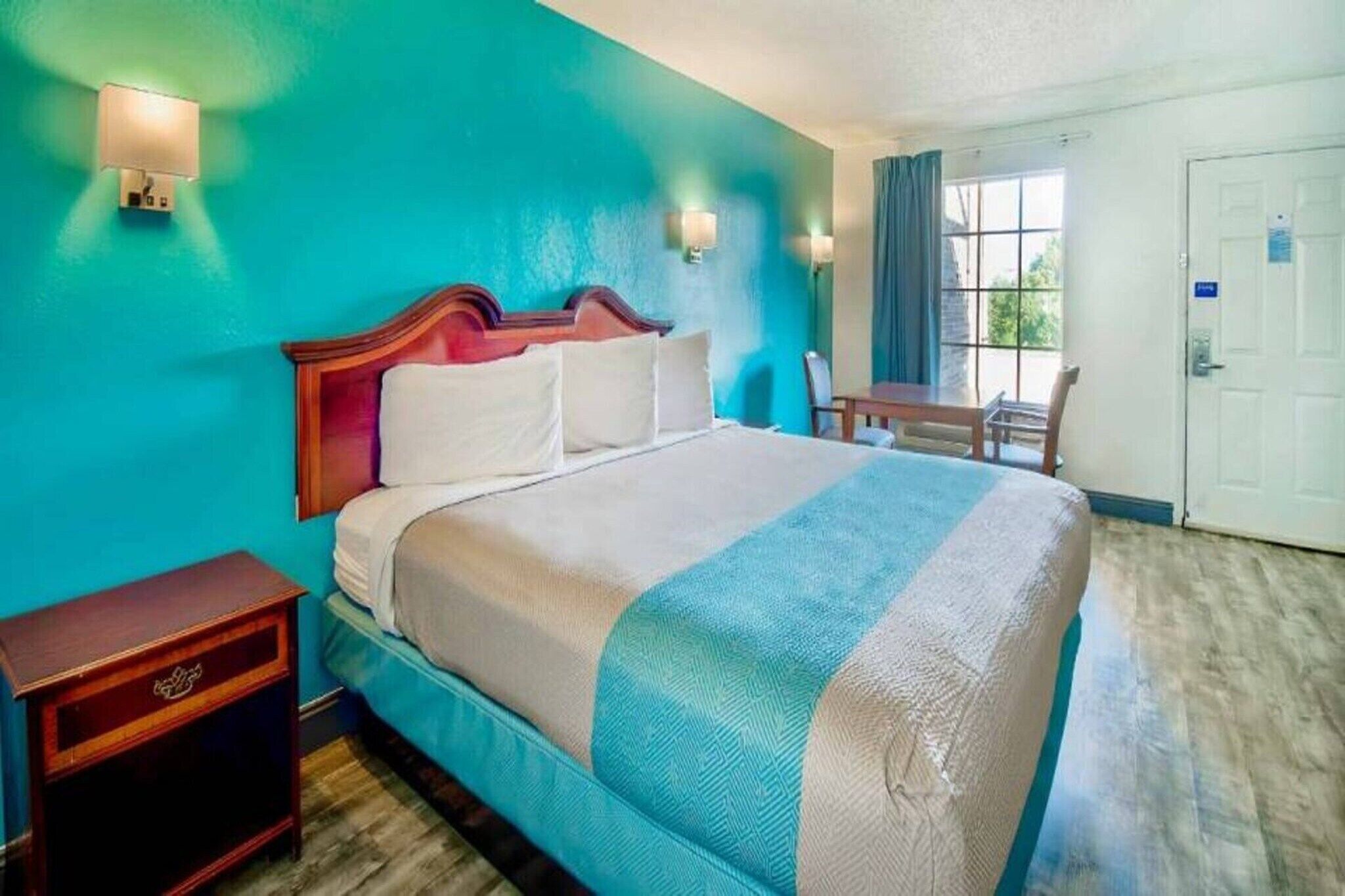 A hotel room with a bed, a desk, and a chair.