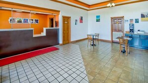 A reception area with a reception desk, a counter, a seating area with chairs, a red carpet, and a tiled floor.