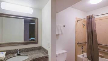 Une salle de bain avec un lavabo sur un plan de travail en granit, des toilettes blanches, une douche avec une porte en verre et un porte-serviettes.