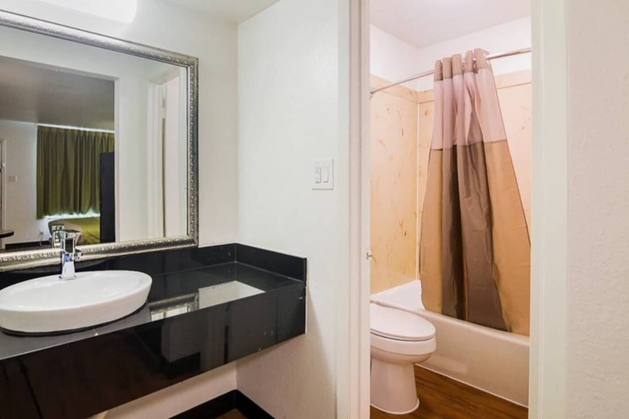 A bathroom with a white sink, a mirror, a toilet, and a shower curtain.