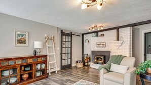 Una sala de estar con chimenea, un sofá, un aparador con puertas de vidrio y una escalera.