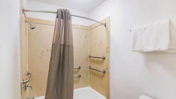 Un baño con ducha, inodoro y toallero.