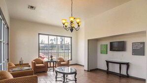 A lobby with a chandelier, seating area, a TV, and a wall with motivational quotes.