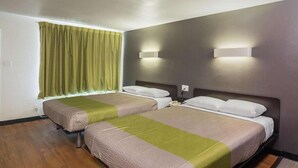 A hotel room with two beds, a window with curtains, and wall-mounted lights.