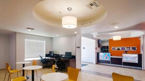 Un espacio de oficina moderno con mesas redondas y sillas amarillas, un mostrador de recepción y una estación de trabajo con computadora.