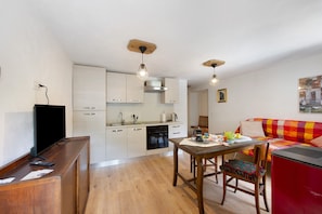 Un espacio habitable compacto con kitchenette, comedor y sofá.