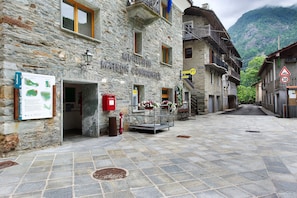 Un edificio de piedra con un letrero que dice 'MUNISTE MAISON COMMERCAT' y una calle con un cartel de límite de velocidad de 30 km/h.