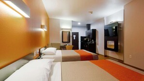 Une chambre d’hôtel avec deux lits, un bureau, un miroir, une télévision et un mini-bar.