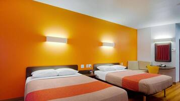 A hotel room with two beds, a small desk, a chair, and a red curtain.