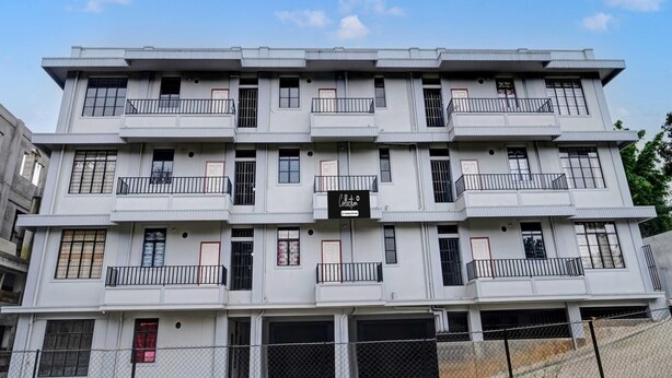 A multi-story building with balconies, a signboard, and a fenced parking area. - Collection O Lapalang Shillong (Shillong)