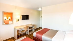 A hotel room with a bed, a desk, a chair, a TV, and a wall-mounted lamp. - Sunny 2-bed Room|Pool|Free Wifi (Redding CA)