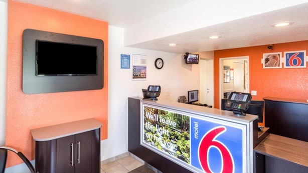 A motel reception desk with a large sign, a television mounted on the wall, and a clock. - Sunny 2-bed Room|Pool|Free Wifi (Redding CA)