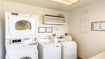 A laundry room with a front-loading washer, a top-loading dryer, and a wall-mounted air conditioner.