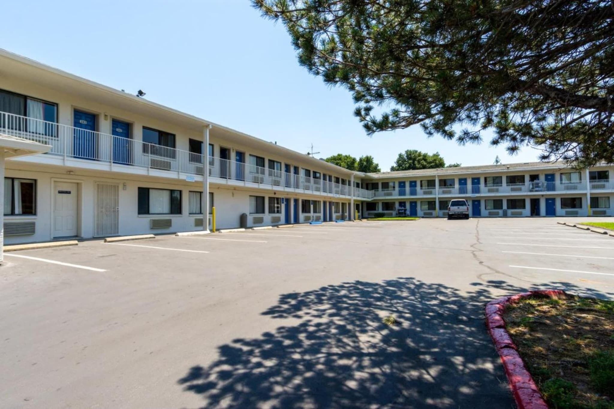 A motel with a central courtyard, multiple balconies, and a parking lot.