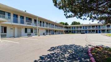A motel with a central courtyard, multiple balconies, and a parking lot.