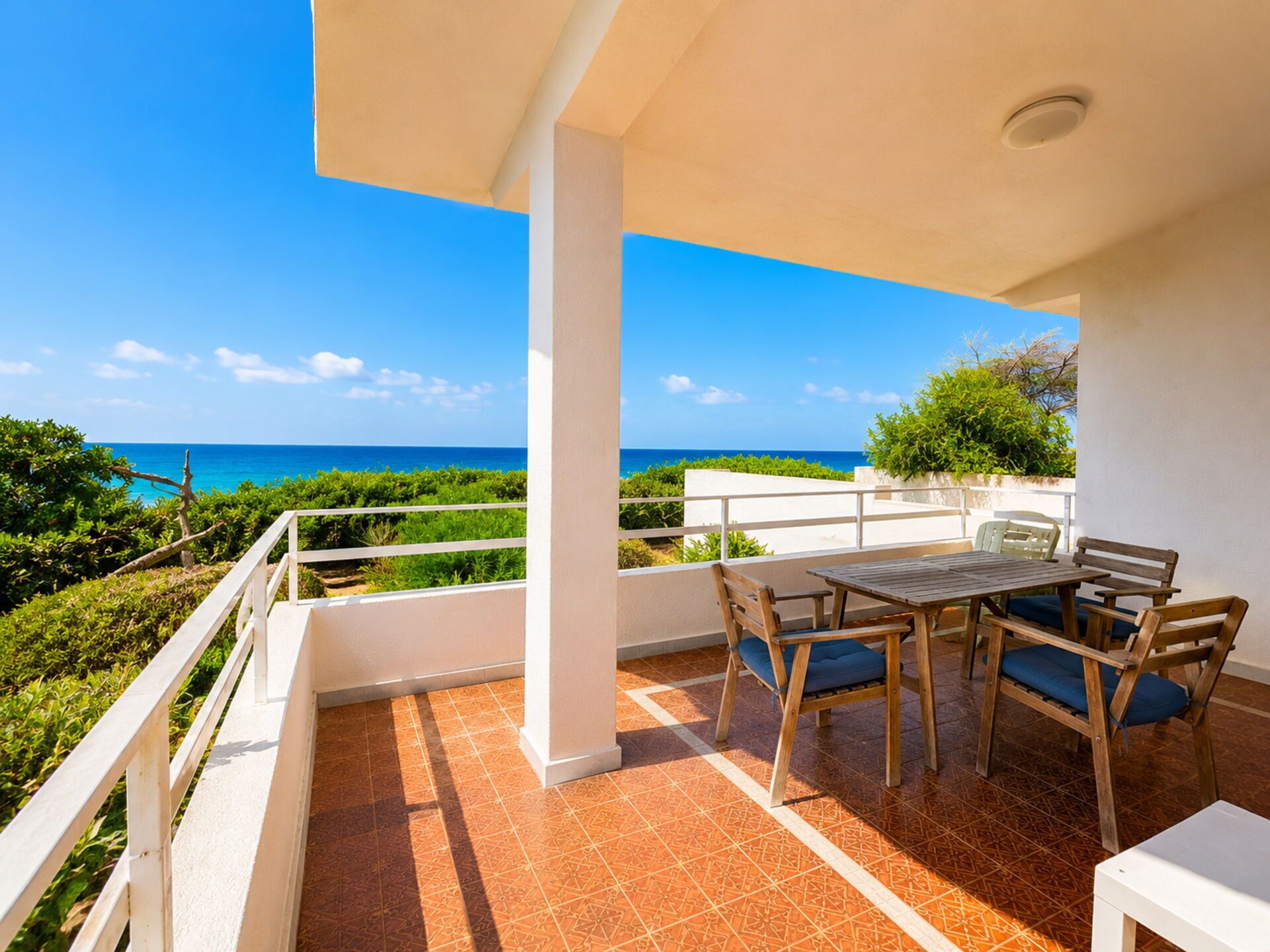 Una terraza con una mesa y sillas, con vistas a un paisaje costero.