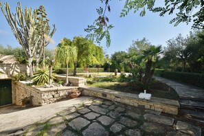 A garden with stone pathways, various plants, and a stone wall. - Villa in Marina Di Modica with 3 bedrooms sleeps 7 (Marina Di Modica)