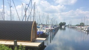 A marina with multiple boats docked, a covered boat house, and calm water.