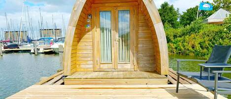 Ein bootförmiges Gebäude aus Holz mit Deck, Tür und einem Stuhl.