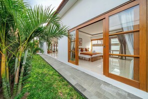 Una casa moderna con un gran ventanal corredera que da a un dormitorio con cama y mesita de noche.