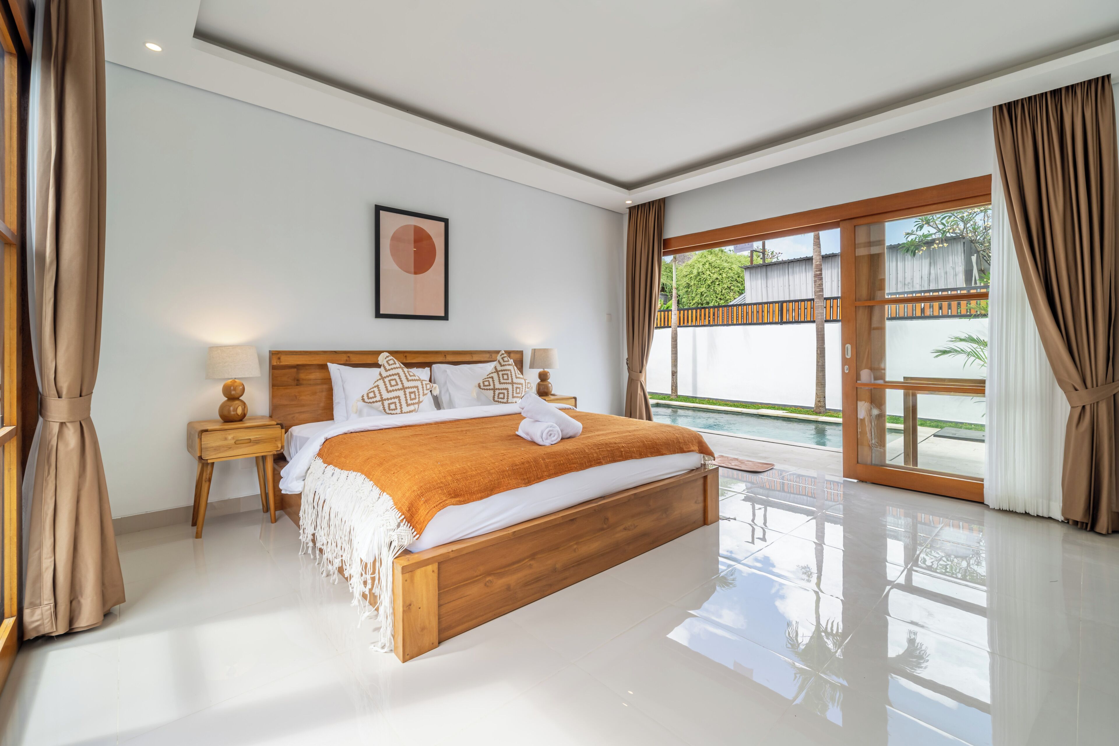 Quarto moderno com cama de madeira, mesa de cabeceira, quadro emoldurado e vista para uma piscina.