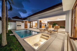 A modern house with a swimming pool, outdoor seating, and a well-lit interior. - Sofia Villas (Kerobokan)
