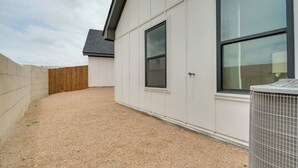 Een gebouw met een grindpad, een houten hek en een airconditioning.