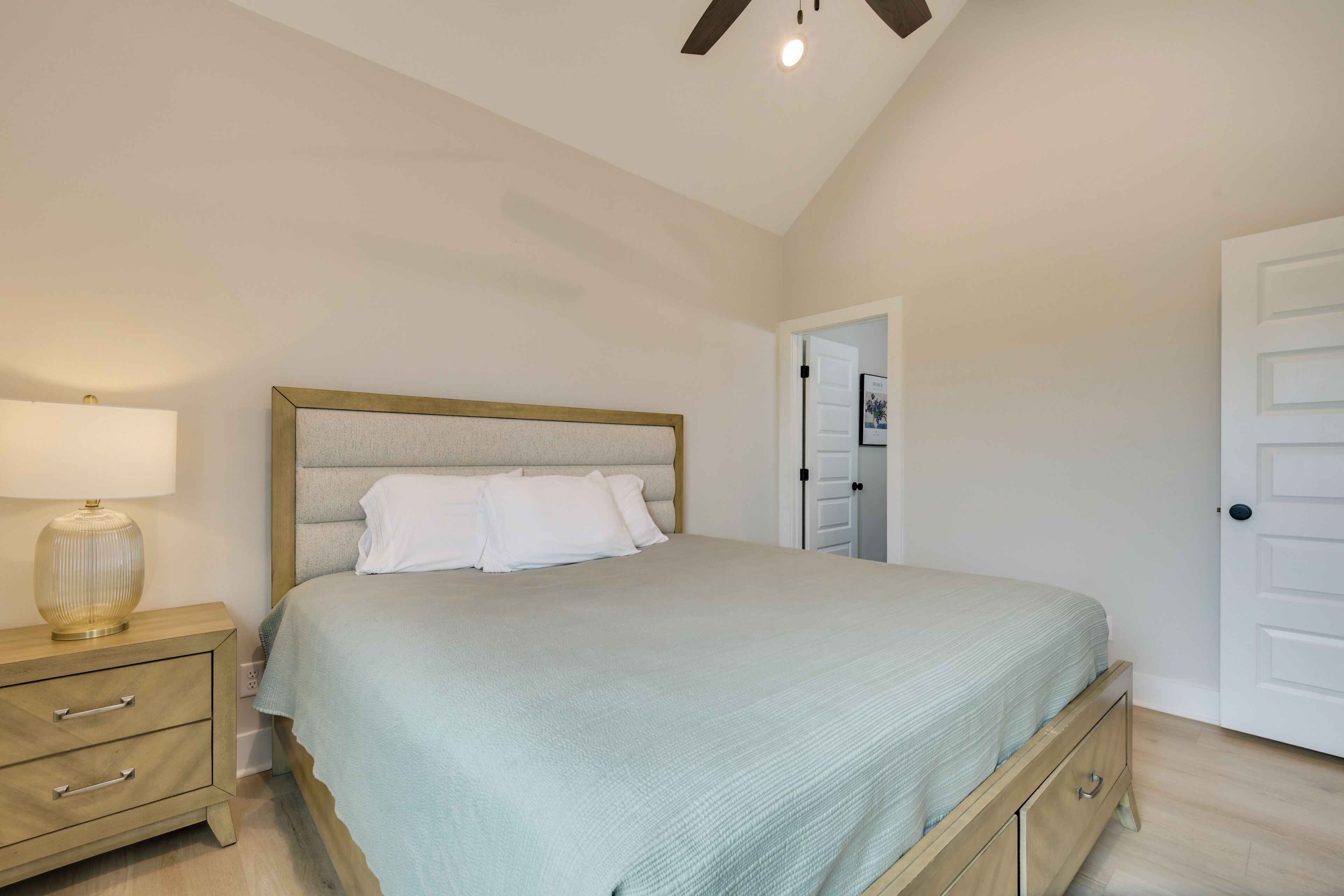 Un dormitorio con cama, mesita de noche y una puerta.