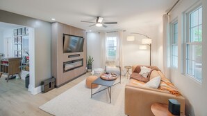 Un salon moderne doté d’un téléviseur à écran plat, d’un ventilateur de plafond, d’un canapé, d’une table basse et d’un espace bureau.