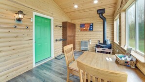 L’intérieur d’un chalet en bois, avec une table à manger, des chaises, une porte verte, un drapeau et une cheminée.