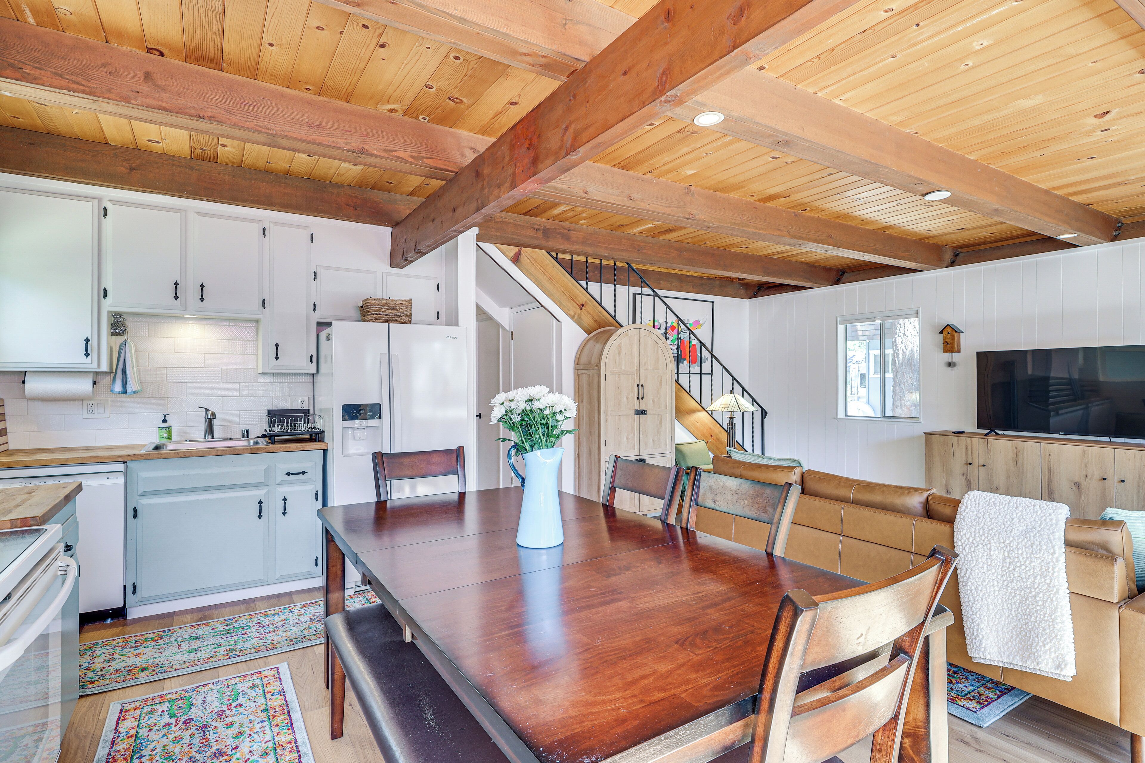 Un'ampia cucina con travi in legno, mobili bianchi e un'area pranzo con tavolo e sedie in legno.