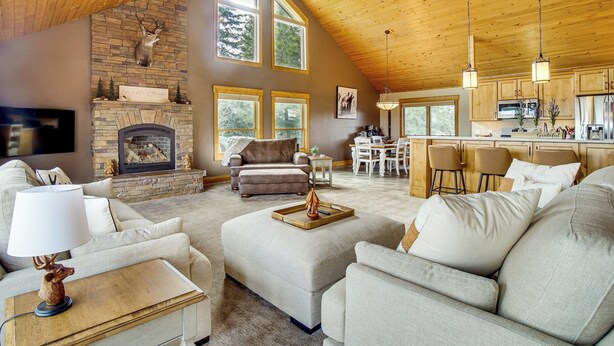 A spacious living area with a fireplace, a dining area, and a kitchen with wooden ceilings and large windows. - Mtn-View Retreat w/ Fire Pits & Grill in McCall! (McCall)