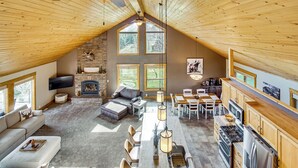 A spacious loft with a high ceiling, a fireplace, a dining area, and a kitchen. - Mtn-View Retreat w/ Fire Pits & Grill in McCall! (McCall)